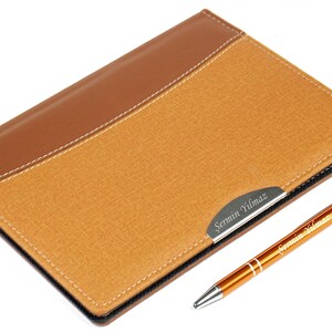 May include: A brown leather-bound notebook with a gold pen. The notebook has a nameplate with the name "Sermin Yilmaz" engraved on it.