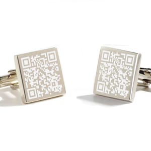 Könnte beinhalten: Ein Paar silberne Manschettenknöpfe mit einem weißen QR-Code-Design.
