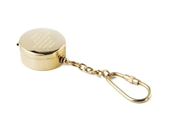 May include: A gold-colored keychain with a round, engraved metal container attached to a chain and a metal clasp. The container has an inscription that reads "Sana as if we were in great spirits and generously distributed."  The inscription is followed by the word "Afton."