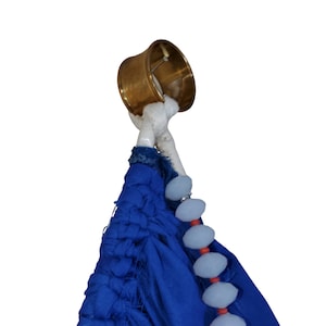 Pu&ograve; includere: Un anello per paralume in ottone &egrave; attaccato a un tessuto blu con una corda bianca. Il tessuto blu &egrave; adornato da una fila di perline azzurre e perline rosse. L'anello del paralume &egrave; di un caldo colore oro.