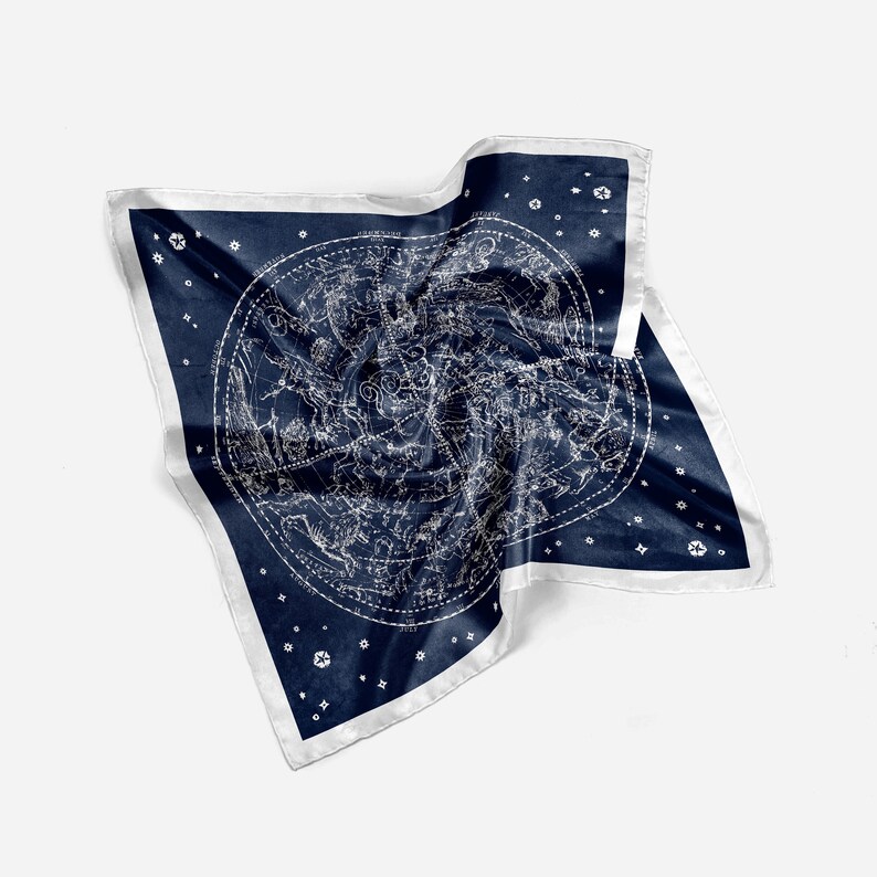 May include: A navy blue silk scarf with a white constellation print. The scarf is folded and draped on a white background.