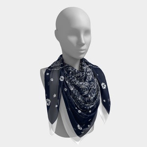 May include: A navy blue and white patterned scarf with a geometric design. The scarf is folded and draped around a mannequin's neck.