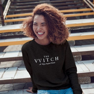 May include: A black long-sleeved sweatshirt with white text that reads "THE VVITCH A New-England Folktale"