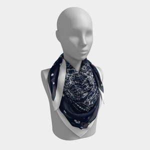 May include: A navy blue and white patterned silk scarf with a white border. The scarf is tied around a mannequin's neck.