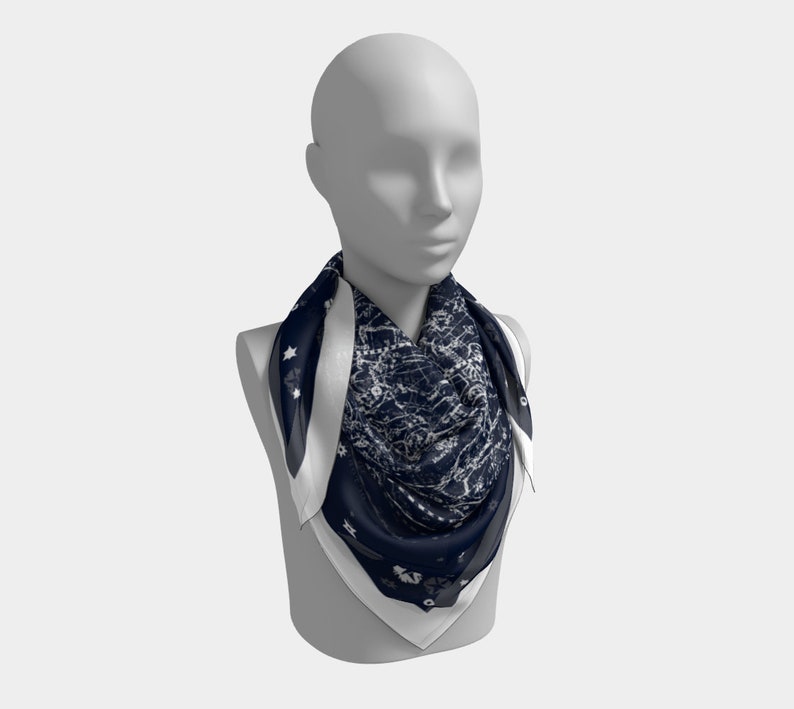 May include: A navy blue and white patterned silk scarf with a white border. The scarf is tied around a mannequin's neck.