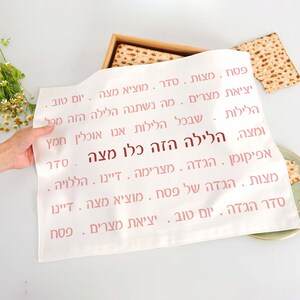 May include: White Passover Seder plate with pink Hebrew text that reads "This is the bread of affliction, all who are hungry come and eat".