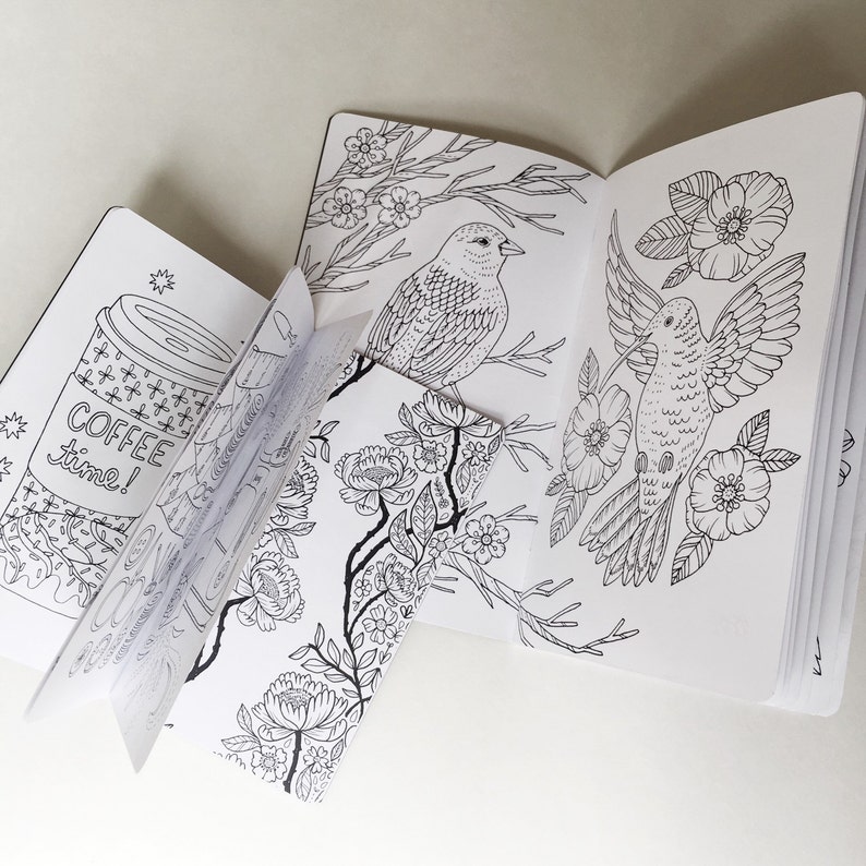 May include: A colouring book with black and white illustrations of birds and flowers. The book is open to a page with a bird perched on a branch and another bird in flight. The text "Coffee time!" is visible on the cover.