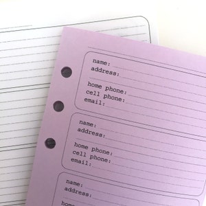 May include: A pink paper notebook with lined pages and holes for a binder. The notebook has a section for contact information with headings for name, address, home phone, mobile phone, and email.