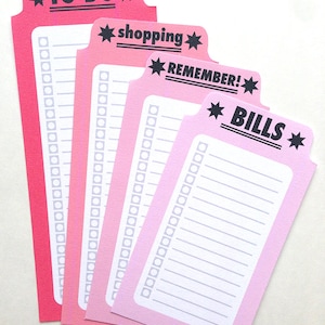 Può includere: Quattro schede di controllo rosa con testo nero. Le schede sono etichettate "TO DO", "shopping", "REMEMBER!" e "BILLS".