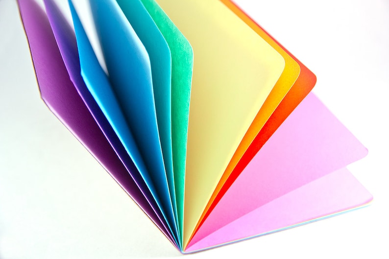 May include: A rainbow fan of colorful paper sheets folded together. The colors are purple, blue, light blue, green, yellow, orange, and pink.