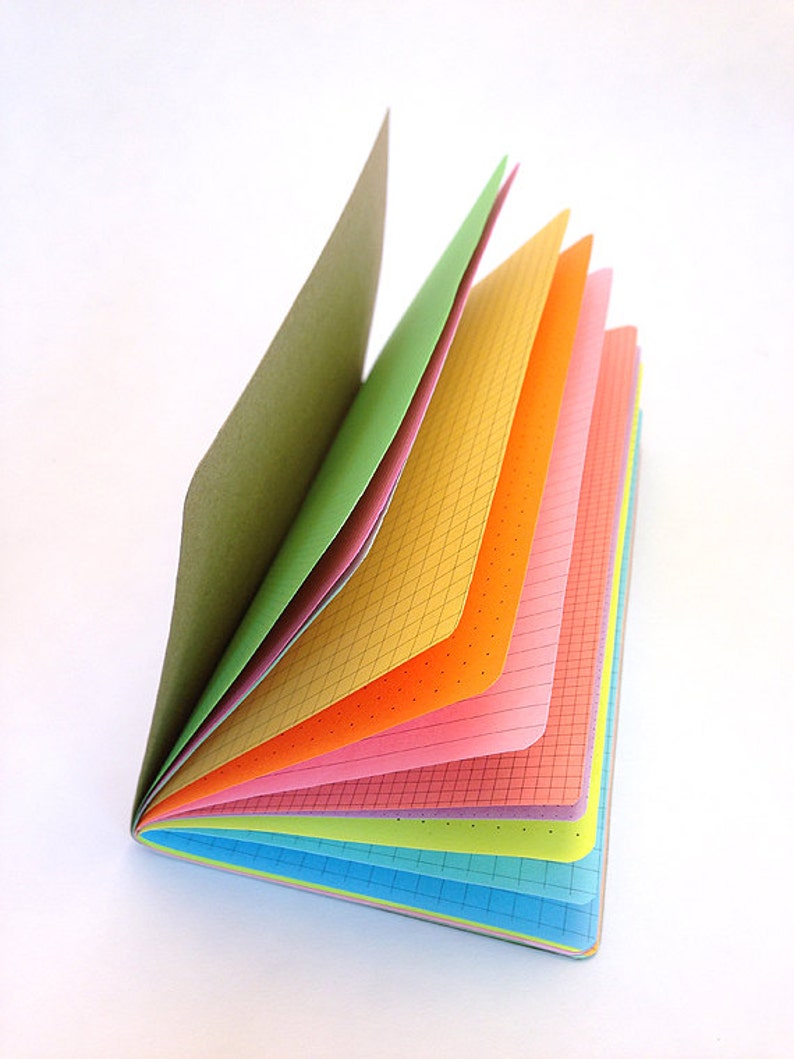 May include: A colorful notebook with a variety of colored pages, including green, yellow, orange, pink, light blue, and dark blue. The notebook is open and fanned out, revealing the different colored pages.