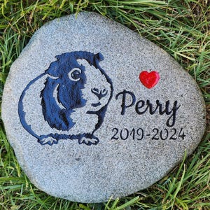 May include: A gray stone memorial with a black and white guinea pig silhouette, a red heart, and the text "Perry 2019-2024".