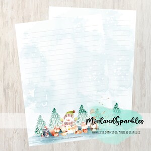 Può includere: Due fogli di carta da lettere a righe con un'illustrazione a tema invernale. Il design presenta un pupazzo di neve, animali del bosco e alberi sempreverdi in stile acquerello. Lo sfondo ha un lavaggio acquerello azzurro chiaro.