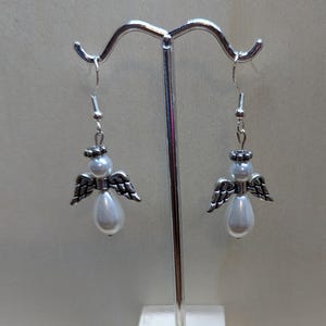 Puede incluir: Un par de pendientes de &aacute;ngel colgantes de plata con detalles de perlas blancas.