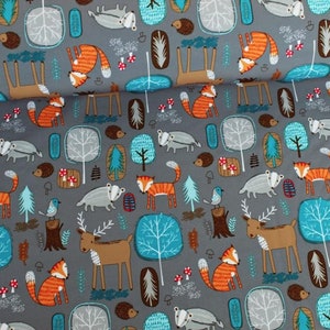 Op de afbeelding: Een grijze stof met een herhalend patroon van bosdieren en bomen. De dieren omvatten herten, vossen, dassen en vogels. De bomen zijn een mix van groen en blauw. De stof is perfect voor knutselprojecten, zoals dekens, kussens en tassen.