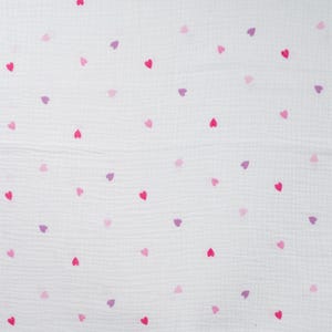 Könnte beinhalten: Ein weißer Musselinstoff mit einem sich wiederholenden Muster aus kleinen, verstreuten Herzen in verschiedenen Rosa- und Violetttönen. Das Textil hat eine geknitterte, leichte Struktur mit einem weichen, atmungsaktiven Aussehen und einem gleichmäßigen Druck.