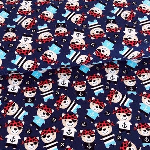 May include: Navy blue fabric with a repeating pattern of cartoon pirate bears. The bears wear red bandanas, eye patches, and sailor hats. Some bears have anchors on their shirts. The fabric is suitable for children's apparel and nautical-themed crafts.