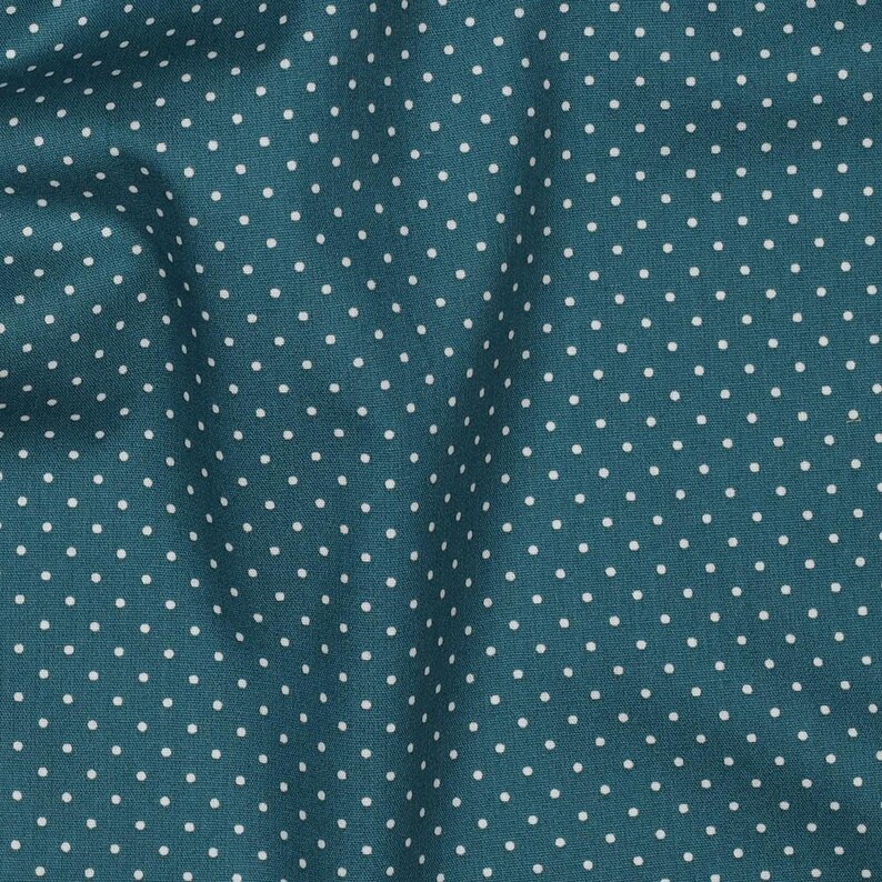 Op de afbeelding: Teal stof met een wit stippenpatroon.