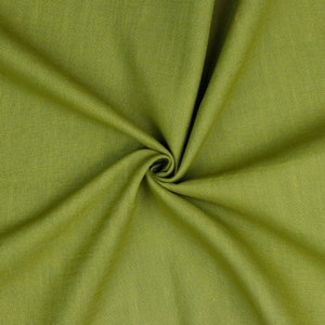 May include: A close-up of a piece of green fabric with a textured weave. The fabric is folded and draped, creating soft folds and wrinkles.