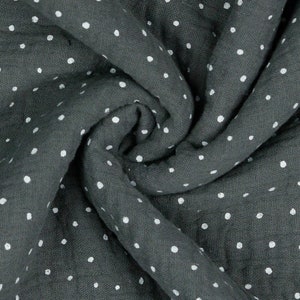 Può includere: Tessuto grigio scuro con un motivo a piccoli pois bianchi. Il tessuto è morbido e drappeggiato, con pieghe e rughe visibili. I pois sono distribuiti uniformemente sul materiale.