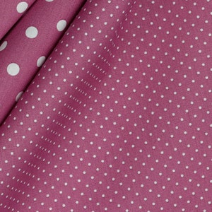 Könnte beinhalten: Nahaufnahme eines Stoffes mit einem sich wiederholenden Muster aus weißen Polka-Dots auf einem tiefrosa Hintergrund. Der Stoff ist gefaltet, wodurch Schatten und Textur entstehen. Die Polka-Dots sind gleichmäßig verteilt und von gleichmäßiger Größe.