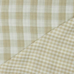 Può includere: Tessuto gingham beige e bianco con una cucitura diagonale. Il tessuto ha una consistenza morbida e testurizzata.