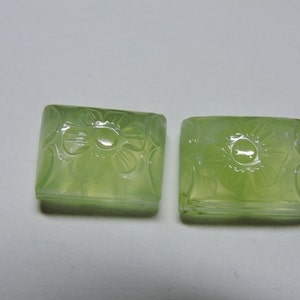 May include: Two square-shaped green gemstone cabochons with carved floral designs.
