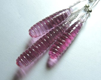 Puede incluir: Tres cuentas de vidrio rosa con un diseño en espiral, enhebradas en un alambre plateado.