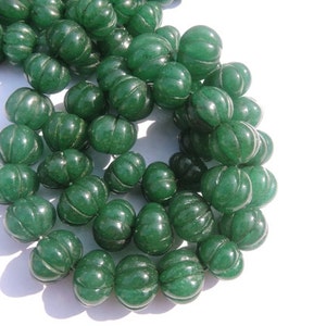 May include: A strand of green glass beads with a ribbed texture. The beads are round and have a slightly translucent appearance.