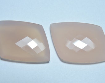 May include: Two pale pink, faceted, gemstone cabochons. The cabochons are cut in a square shape with rounded corners.