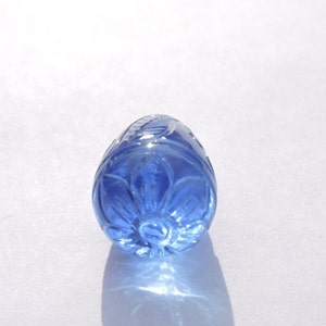 Peut inclure: Une pierre précieuse bleue sculptée avec un motif floral. La pierre précieuse est de forme ovale et a une surface lisse et polie.