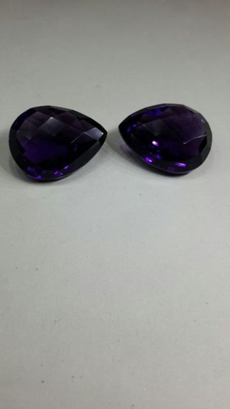 Pode incluir: Duas gotas de pedra preciosa de ametista de cor p&uacute;rpura profunda, cortadas em forma de l&aacute;grima facetada.