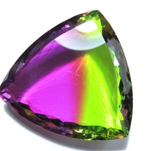 Op de afbeelding: Een driehoekig geslepen edelsteen met een groene en paarse kleurgradiënt. De edelsteen is gefacetteerd en heeft een hoge glans.