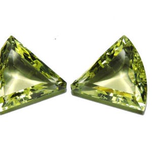Puede incluir: Dos piedras preciosas verdes de forma triangular con un corte facetado.