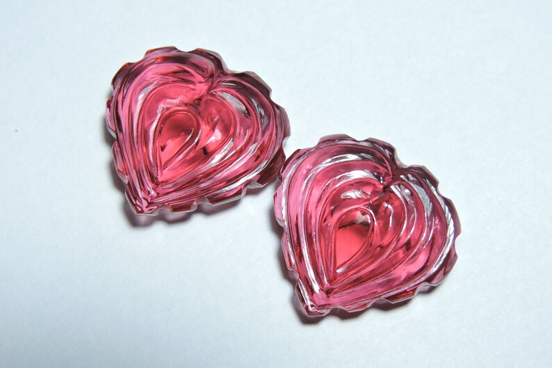 May include: Two pink heart-shaped glass pieces with a layered, textured design.