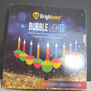 May include: A square product box for Brightown Bubble Lights featuring a graphic of nine multicolored bubble light bulbs. The text reads Brightown BUBBLE LIGHTS, End-to-end connect up to 9 strands, 1 replacement fuse included, and 9 COUNT / MULTICOLOR.
