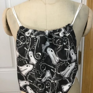 Puede incluir: Una bolsa de cordón negro con un patrón de fantasmas blancos y "Boo".