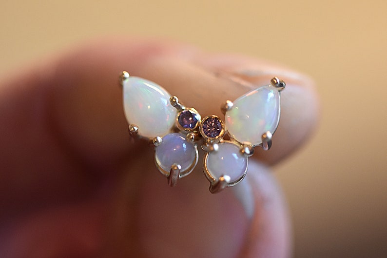 Puede incluir: Un anillo con forma de mariposa que presenta dos &oacute;palos en talla pera para las alas superiores, dos &oacute;palos redondos en cabuj&oacute;n para las alas inferiores y dos peque&ntilde;as piedras redondas de color p&uacute;rpura en el centro, montados en metal.