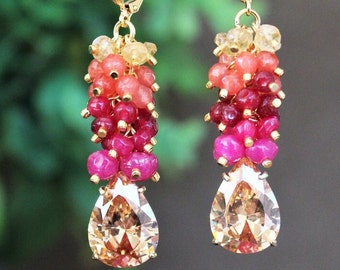 May include: Gold-toned dangle earrings featuring a cluster of colorful beads in shades of pink, red, and yellow, with a large, pear-shaped, champagne-colored crystal at the bottom. The earrings have a lever-back closure.