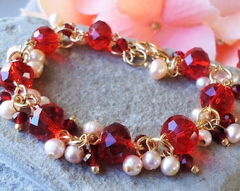 May include: A gold chain bracelet adorned with faceted red beads and small, round, off-white pearls. The bracelet features a delicate design with multiple strands and gold-colored accents, creating a sparkling and elegant accessory.