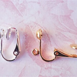 May include: Two earring clips, one silver and one gold. Both clips have a round ball on the top and a spring-loaded clasp.