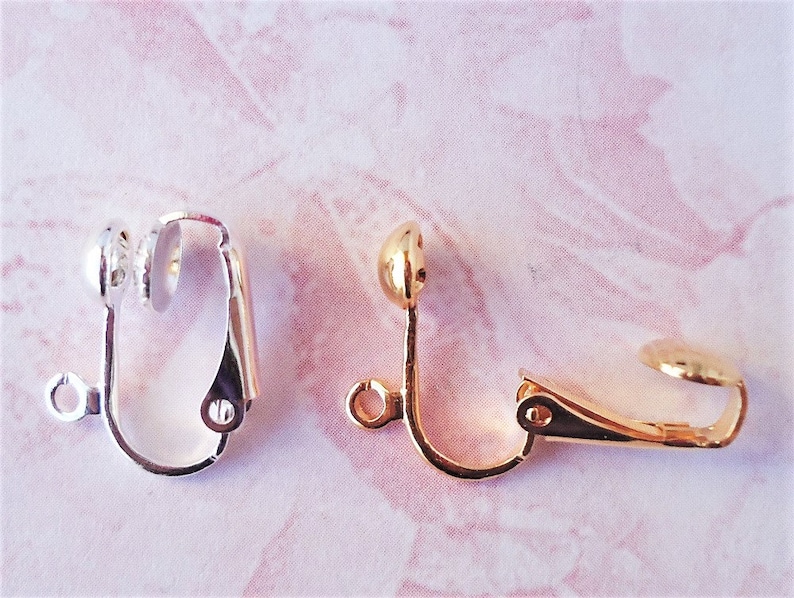 May include: Two earring clips, one silver and one gold. Both clips have a round ball on the top and a spring-loaded clasp.