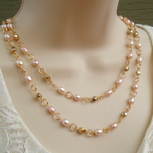 May include: A double-strand necklace with pink pearls and gold-toned metal beads.