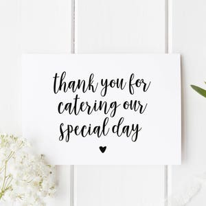 May include: White card with black calligraphy that reads "thank you for catering our special day" with a small black heart at the bottom.