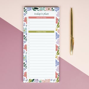May include: A floral-patterned notepad with the text "today's plan" and a gold pen. The notepad has sections for "must do today" and "if there's time". The floral design includes pink, blue, and purple flowers.