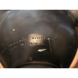 May include: Close-up of a black Mickey Mouse figurine. The text on the figurine reads "WALT DISNEY PROD. / MICKEY MOUSE MADE IN TAIWAN". The number "5" is also visible.