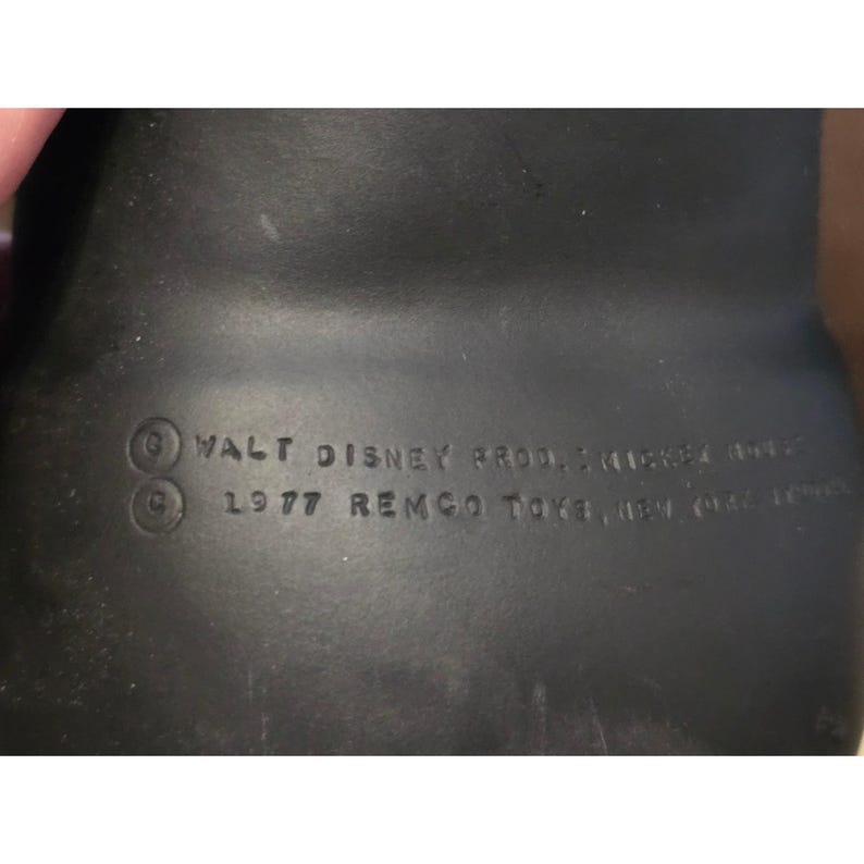 May include: A close-up of a black vintage toy with the text "WALT DISNEY PROD. MICKEY MOUSE" and "1977 REMCO TOYS, NEW YORK, N.Y. 10017". The toy is likely a collectible item.