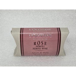 May include: A bar of L'Occitane Rose Neroli bath soap. The soap is wrapped in a light beige paper with a pink label. The label features the brand name, product name, and scent details in English and French.