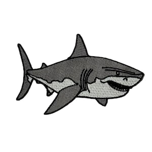 May include: Embroidered patch featuring a stylized shark in shades of gray and white. The shark has a detailed design with visible teeth and fins, perfect for adding to clothing or accessories.