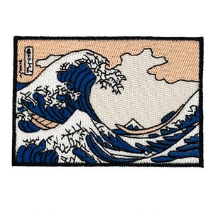 May include: Embroidered patch depicting a large ocean wave in shades of blue and white, with a boat and mountain. The background is beige and off-white. The design is a stylized representation of a famous Japanese artwork.